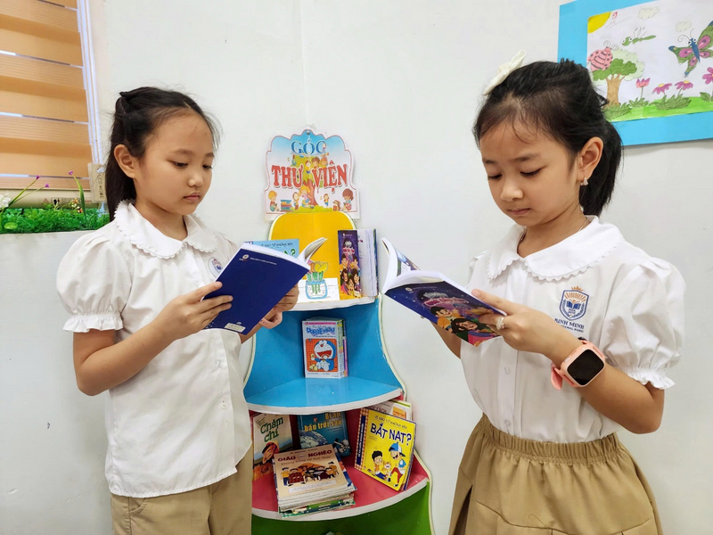 Các em học sinh chăm chú đọc sách tranh “Bí mật Quả cầu tím”